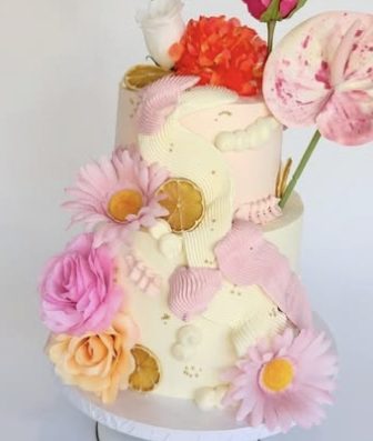 Two-tier cream cake decorated with pink and orange flowers